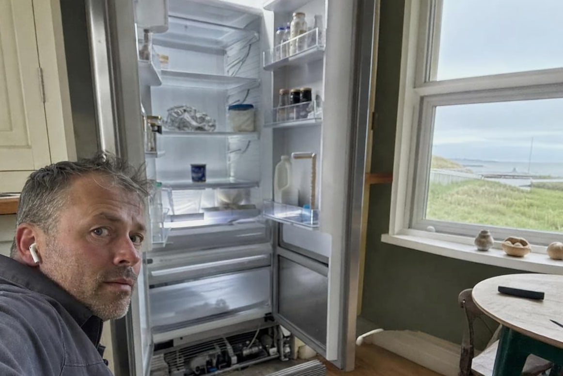 Open built-in refrigerator in a Monterey Peninsula kitchen with the water visible through the window