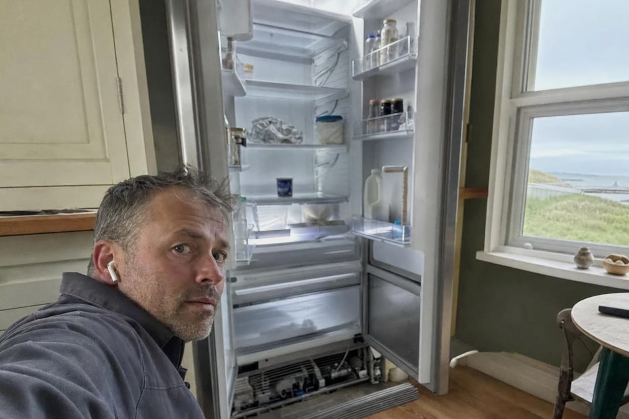 Coastal kitchen with a built-in refrigerator standing open and the water visible through the window