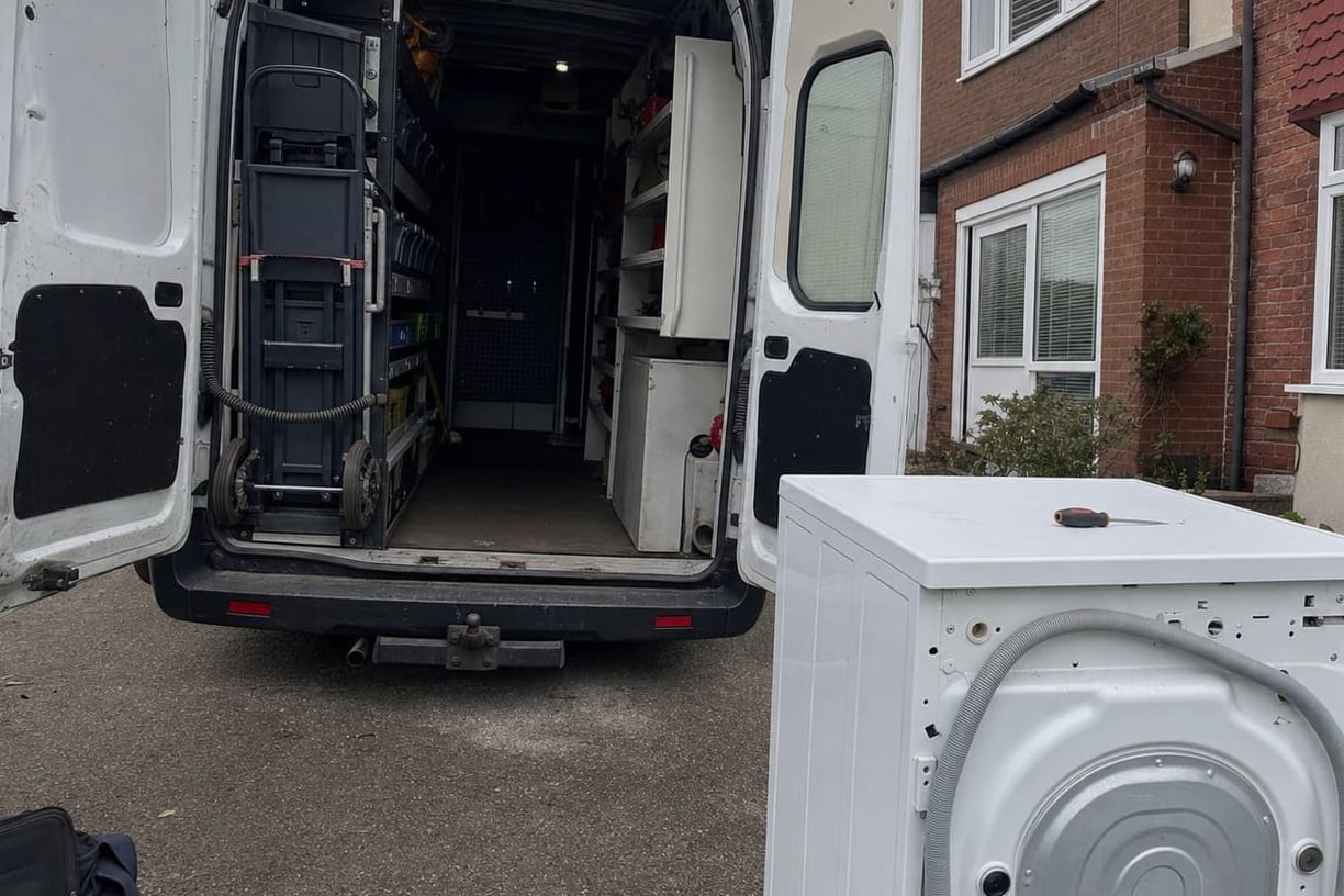 Service van with the rear doors open in a driveway, tools and parts racked inside and an appliance drawn out onto the drive