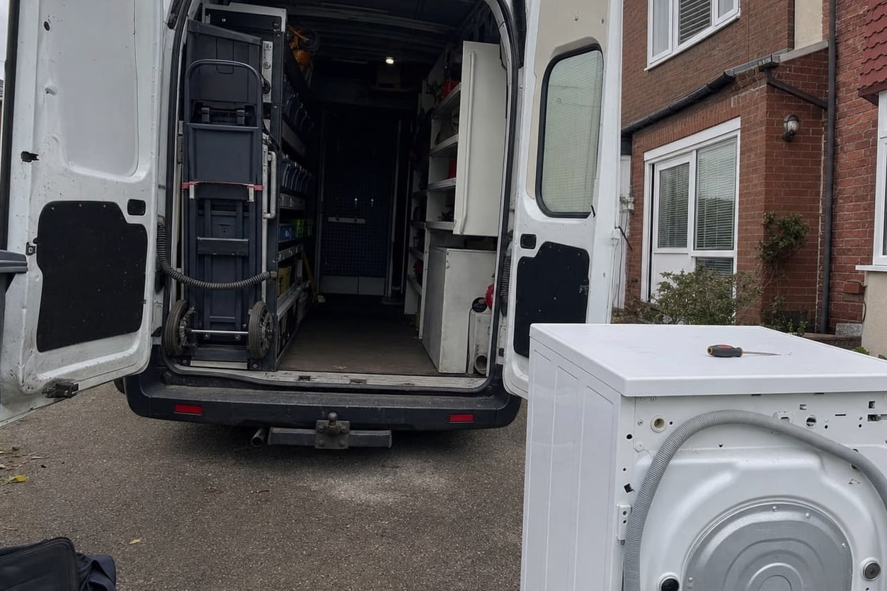 Service van with the rear doors open in a driveway, tools and parts racked inside and an appliance drawn out onto the drive
