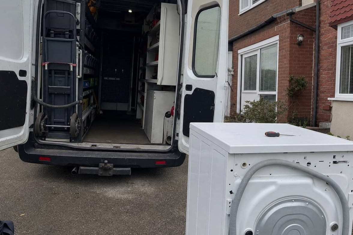 Service van with the rear doors open in a driveway, tools and parts racked inside and an appliance drawn out onto the drive